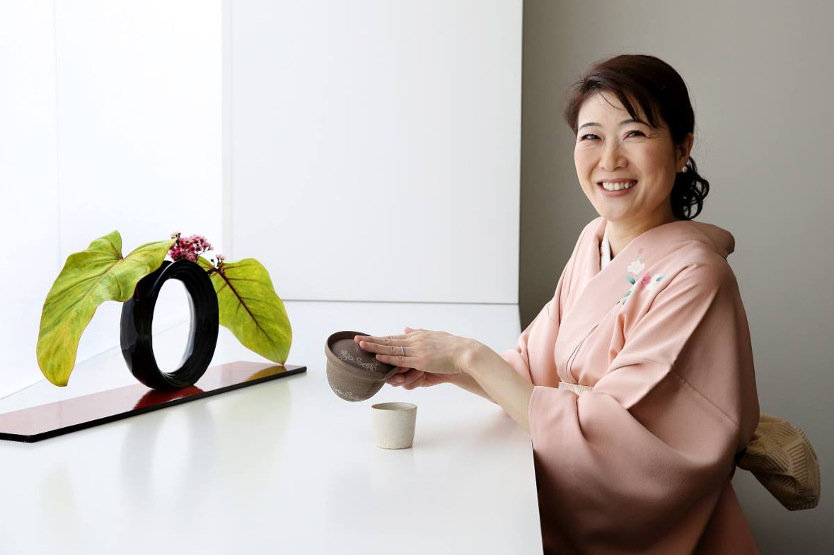 Mme Emiko Okamoto qui sert du thé en souriant